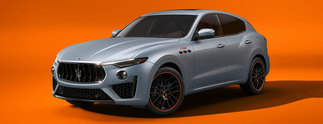 A silver Maserati Levante SUV with orange-rimmed black wheels, set against a vibrant orange and gray background.